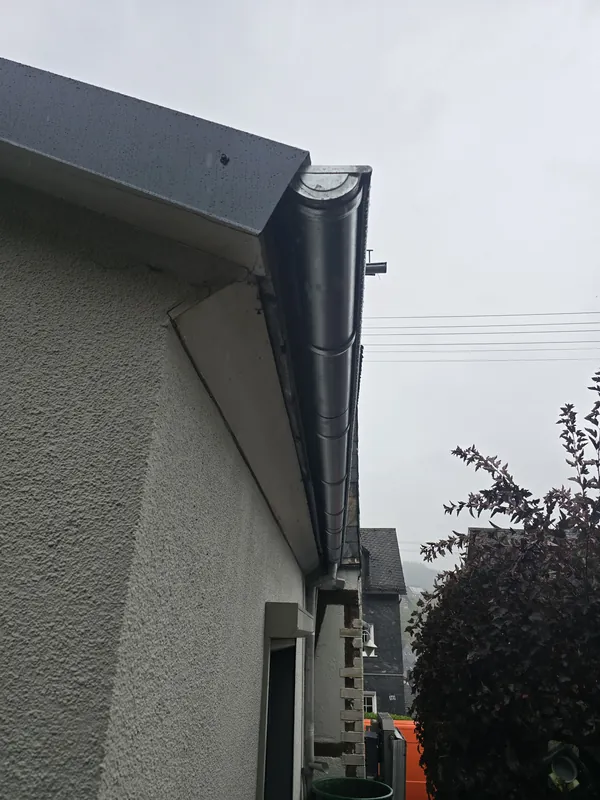 Dunkle Rinne und Fallrohr am Giebel eines Anbaus